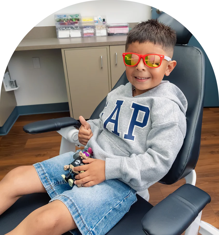 Young patient in sunglasses giving a thumbs up from the dental chair at Pleasant Valley Pediatric Dentistry